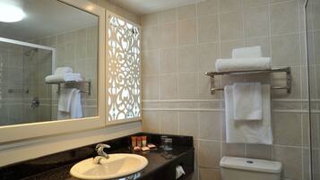 A bathroom with a sink, mirror, shower, and towel rack.