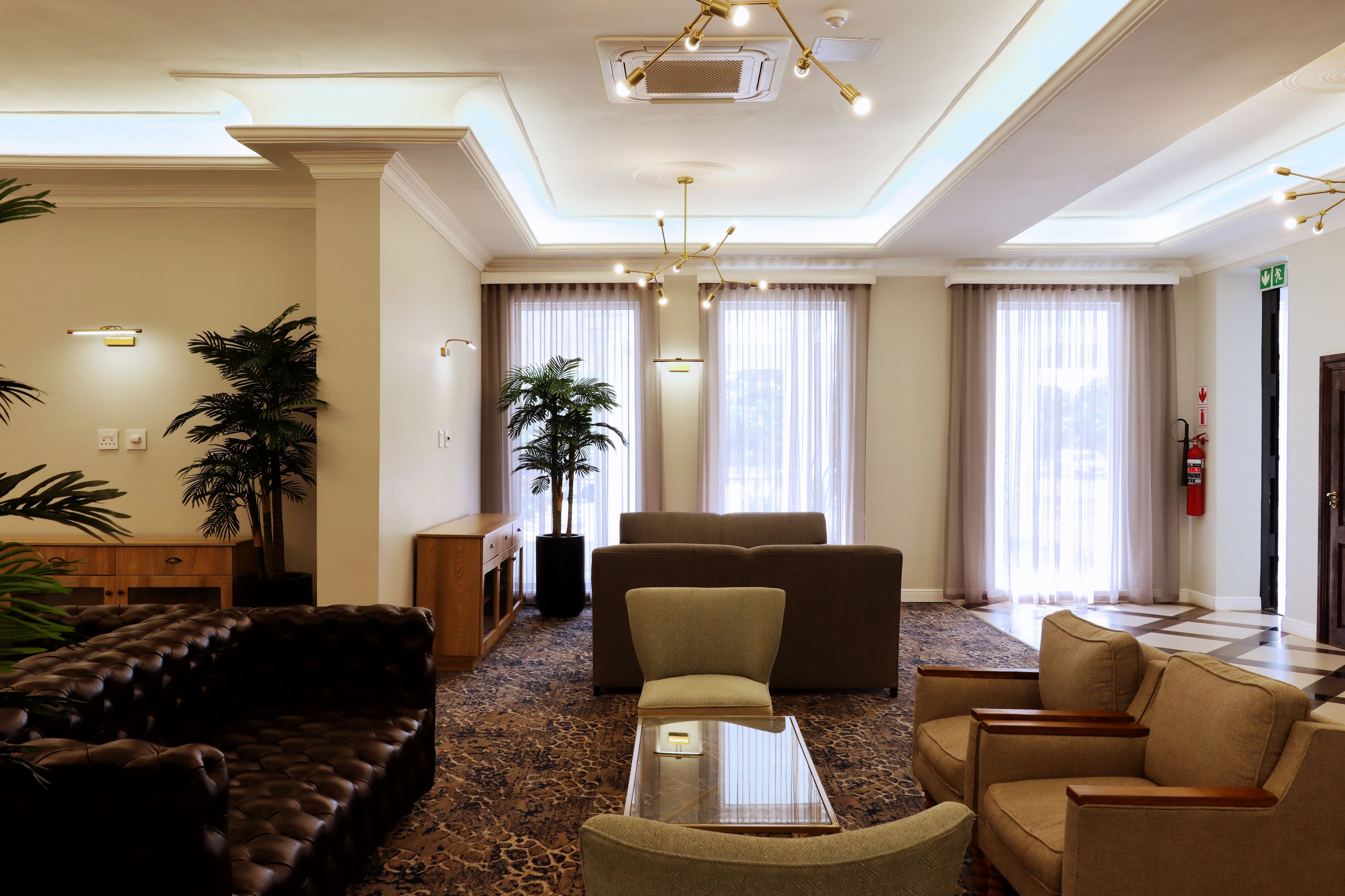A hotel lobby with a seating area, a coffee table, and a large plant.