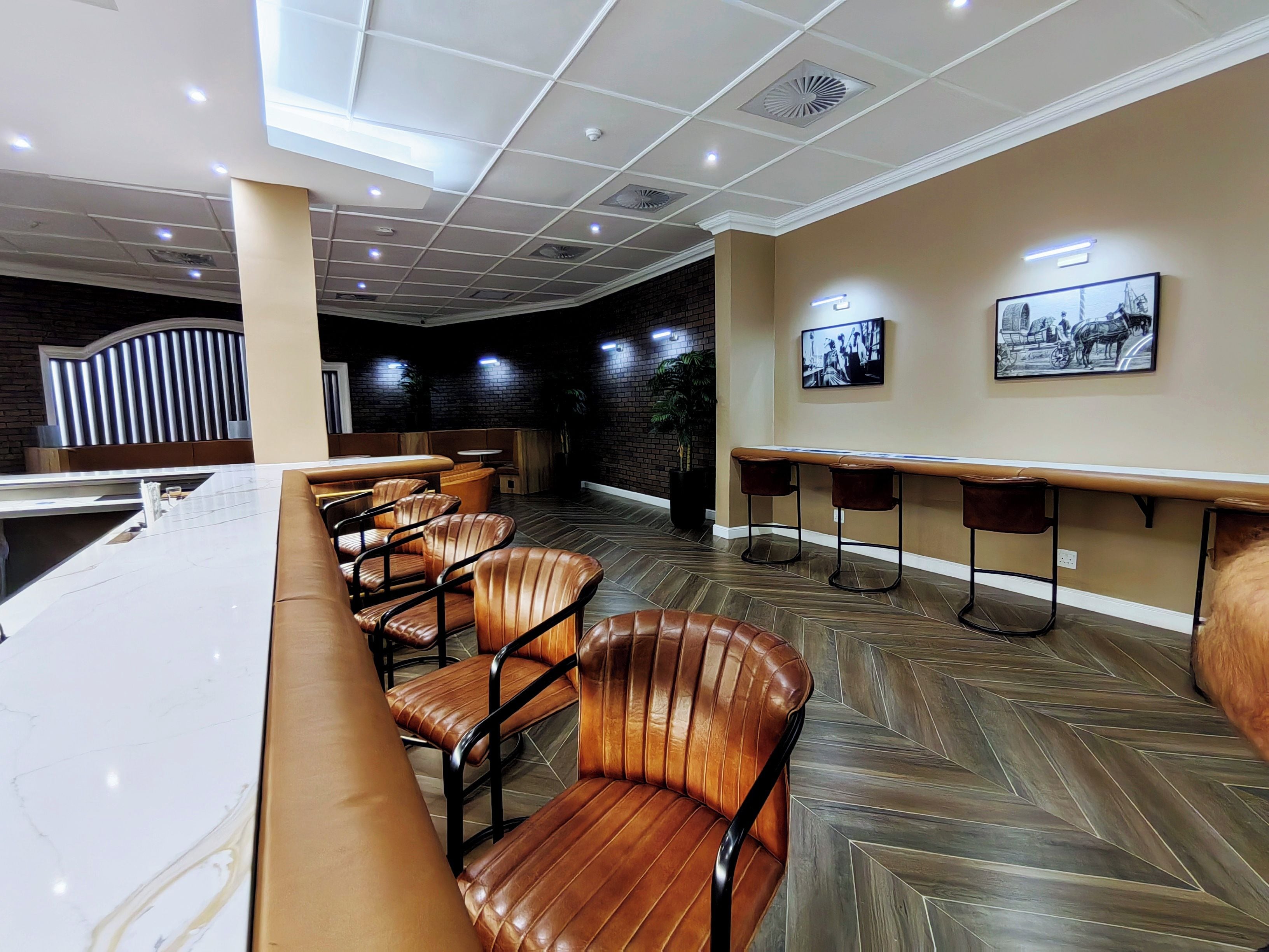 Um interior moderno com área de bar, assentos de couro e padrão de piso em padrão herringbone.
