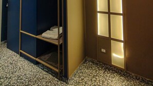 Quarto de hotel com beliche, uma grande janela com painéis iluminados e piso de azulejos.