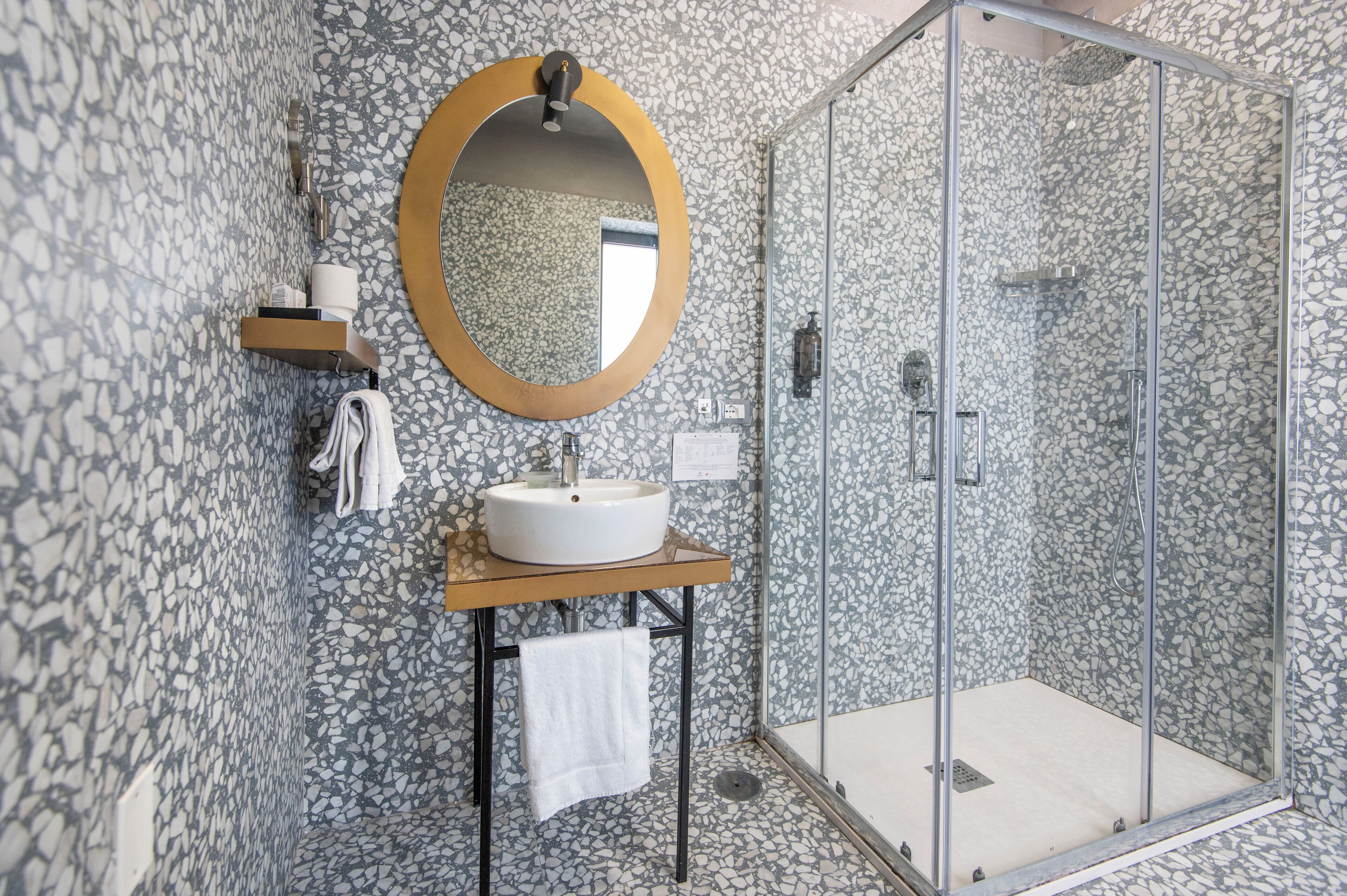 A modern bathroom with a freestanding sink, a round mirror, and a glass-enclosed shower.