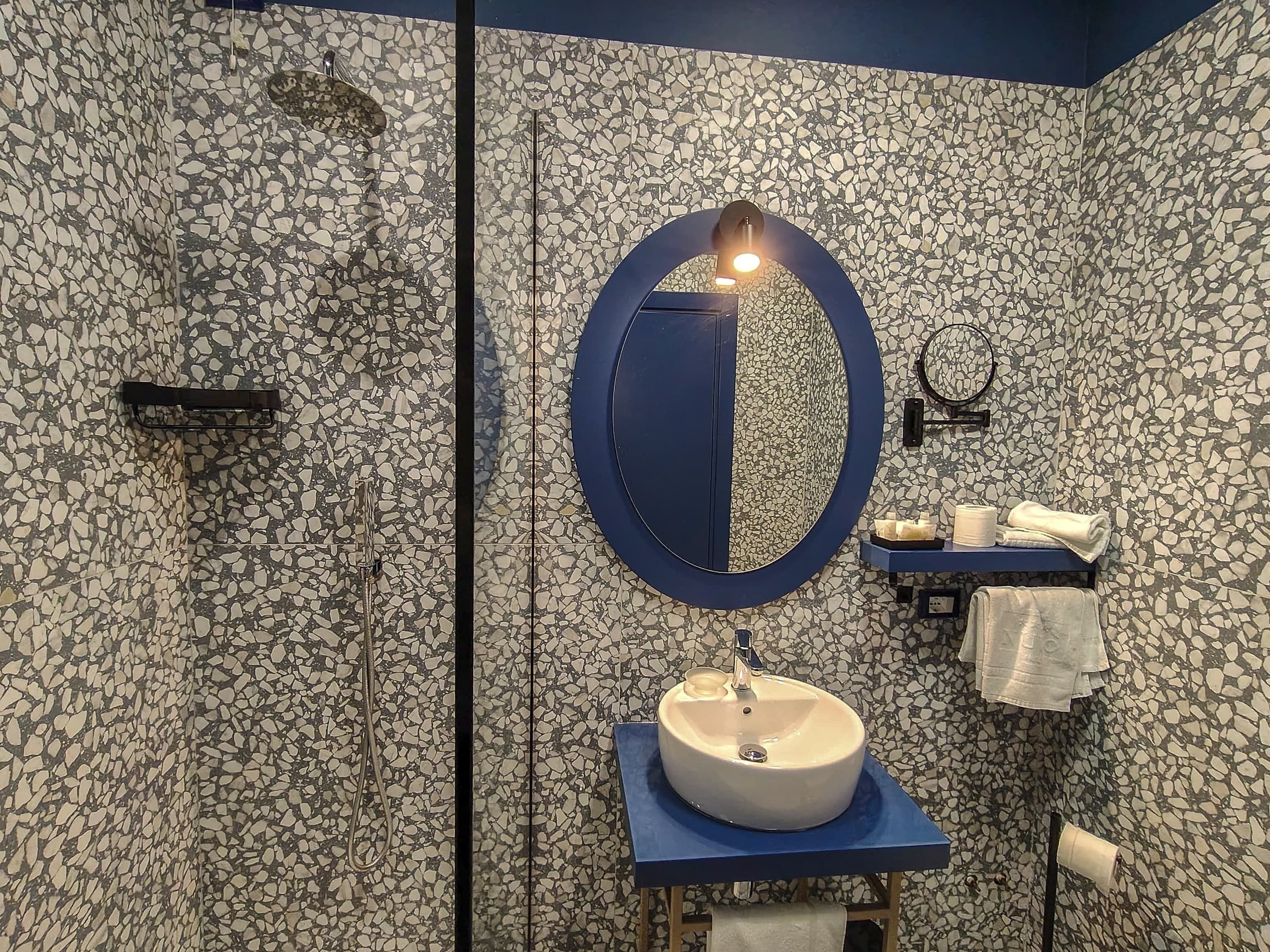 Un bagno con uno specchio rotondo, un lavandino e un porta asciugamani.