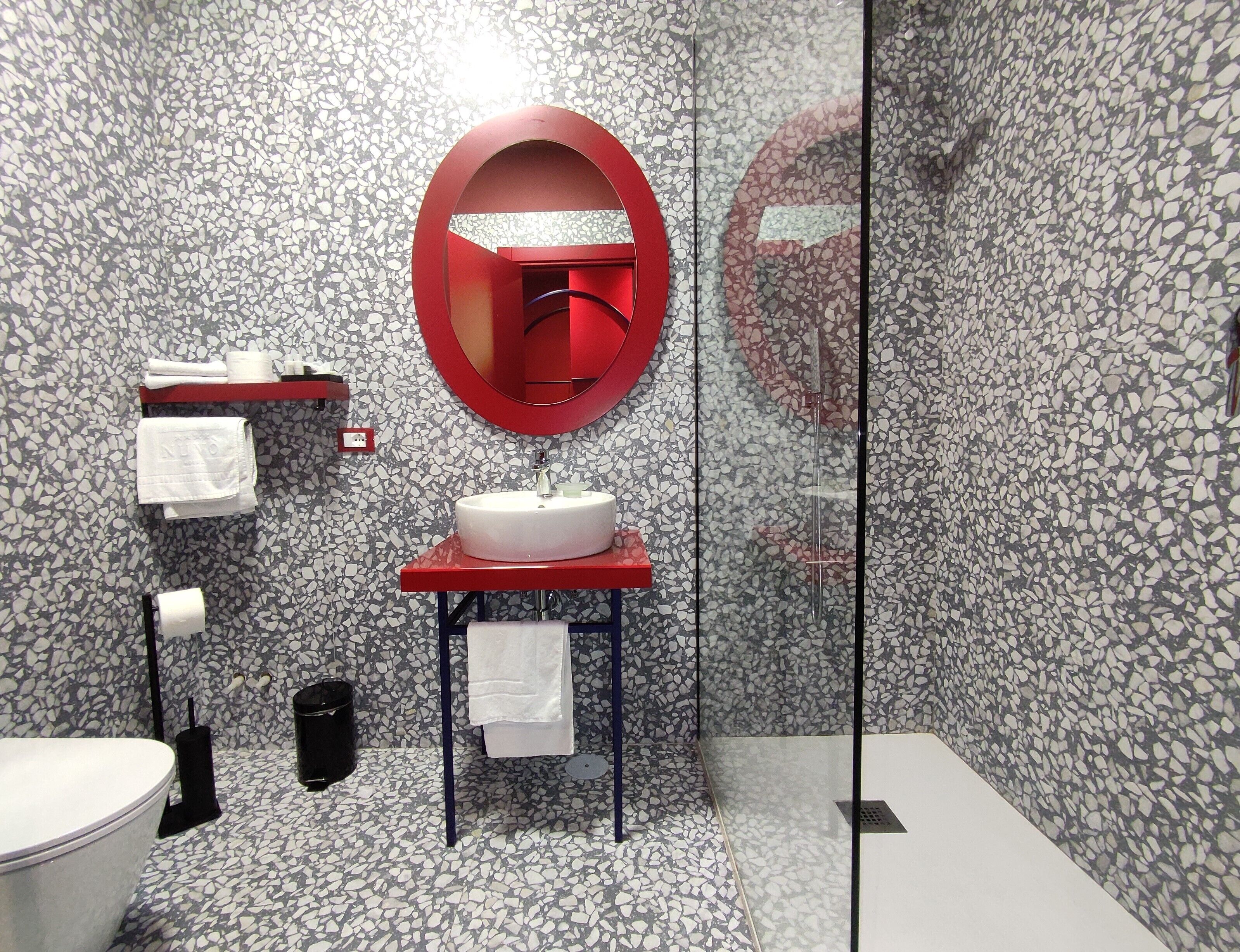 A modern bathroom with a round mirror, a white sink, and a toilet.