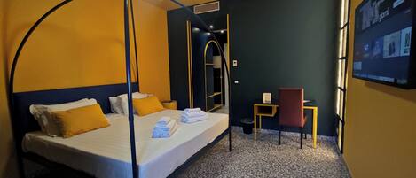 A hotel room with a four-poster bed, a desk, and a chair.