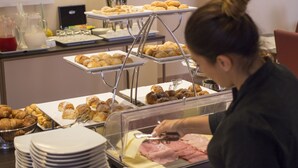 Buffet montado com diversos alimentos e uma pessoa servindo.