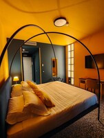 Una habitación de hotel con cama, escritorio, silla y espejo.