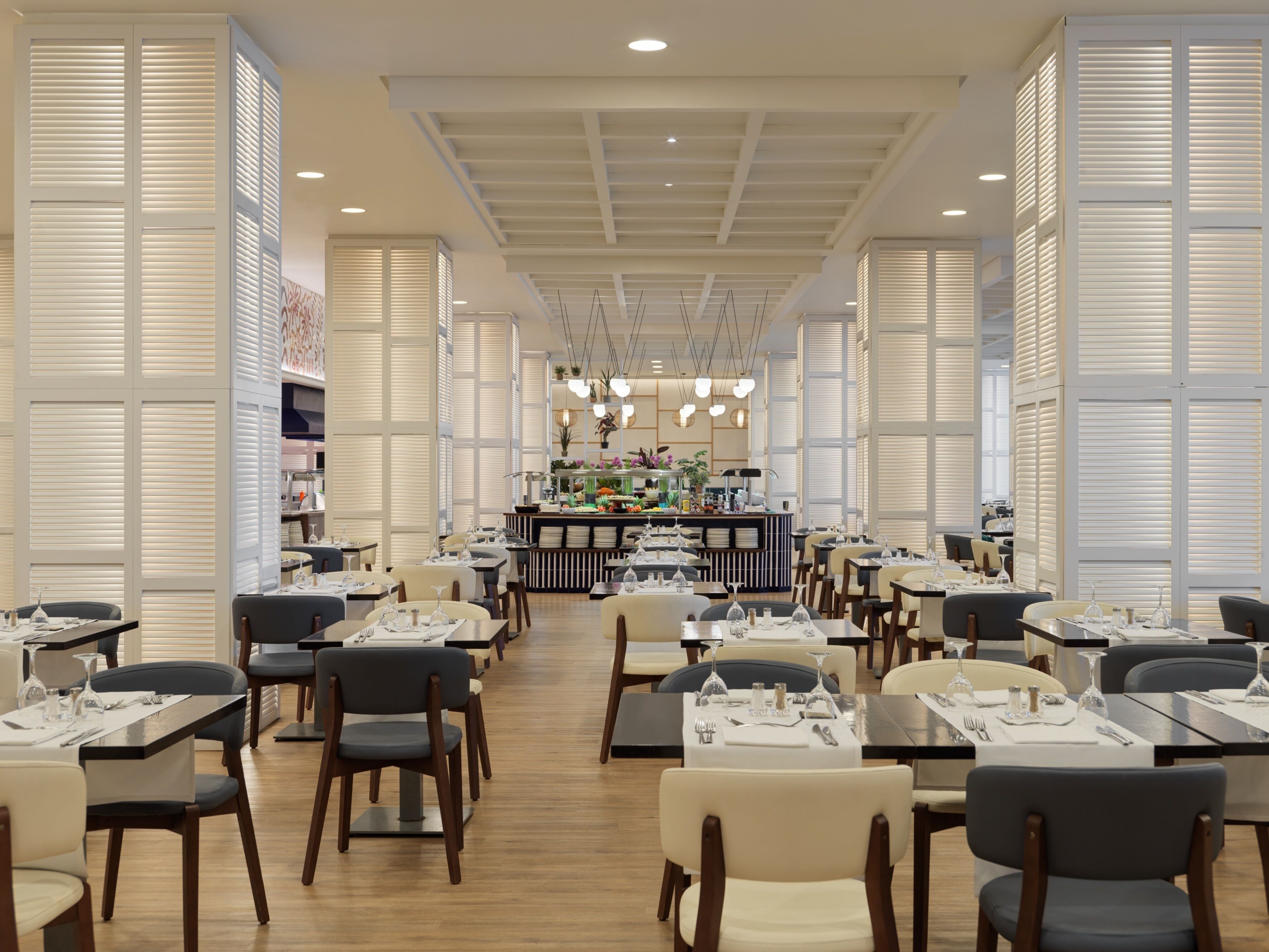 A spacious restaurant with high ceilings, modern lighting, and a central bar area.