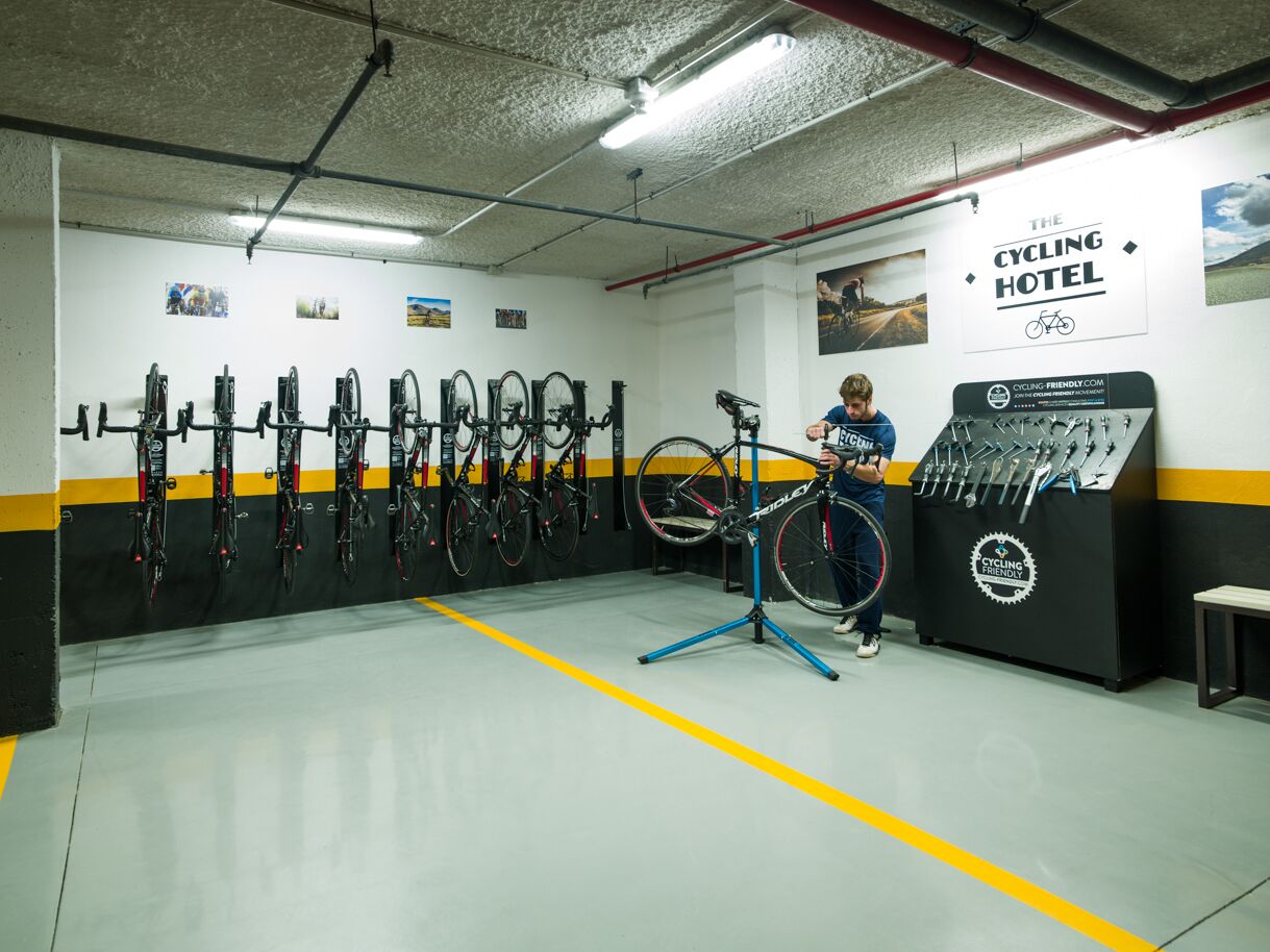 Un hotel para ciclistas con un soporte para bicicletas de pared, una bicicleta estática y un taller de reparación de bicicletas.