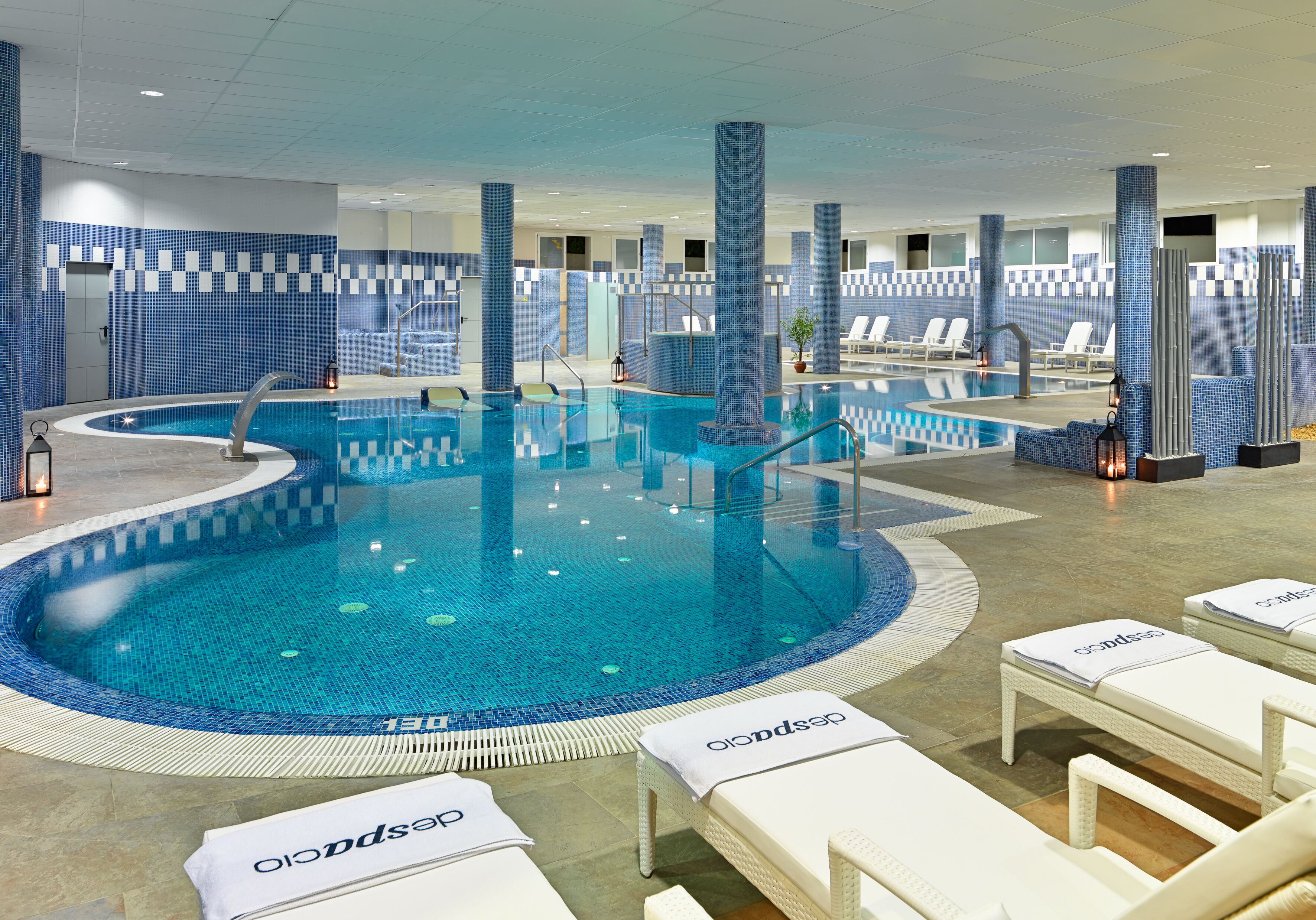Ein Hallenbad mit gefliesten Wänden und Liegestühlen.