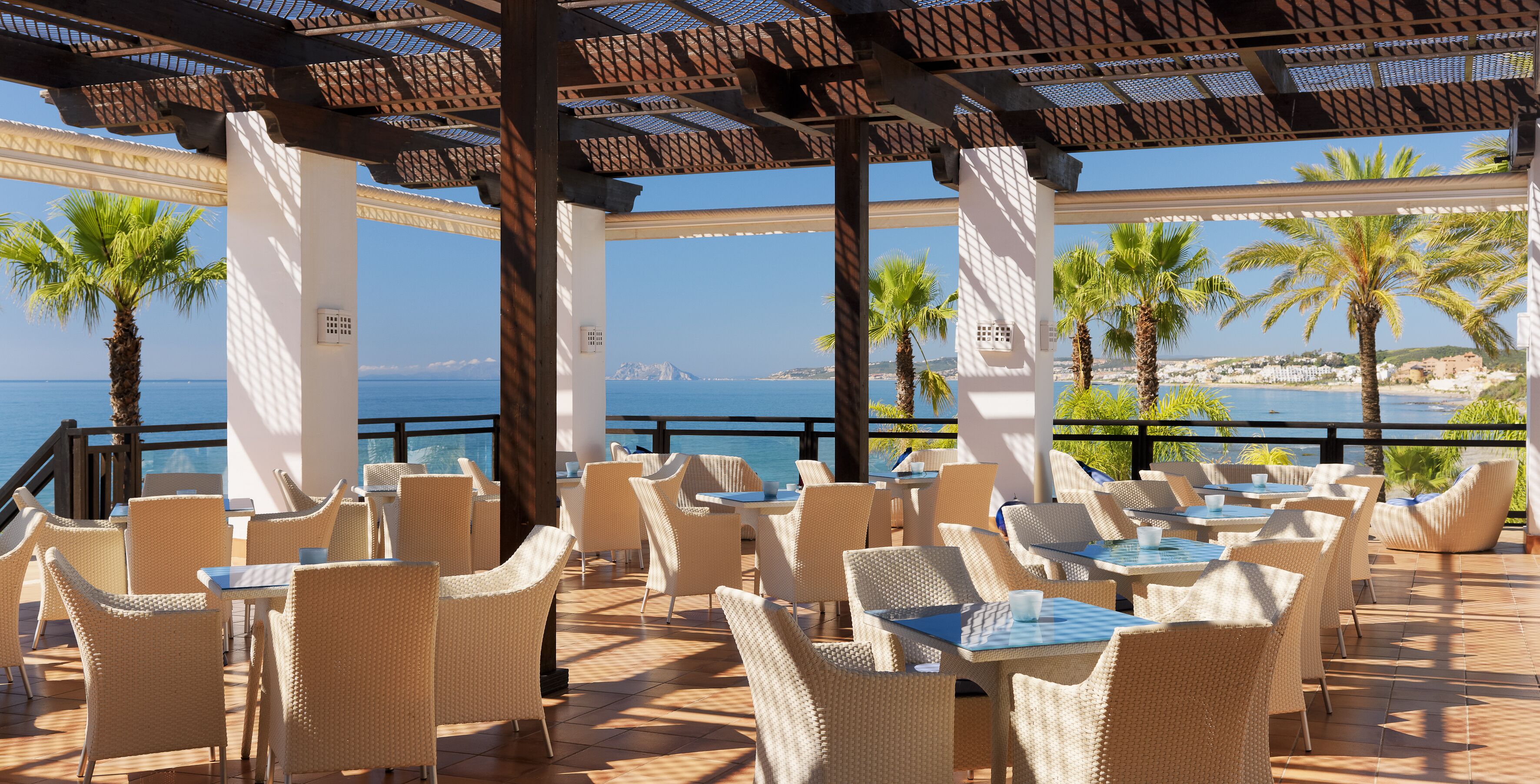 Een restaurant aan zee met rieten meubels en uitzicht op de oceaan.