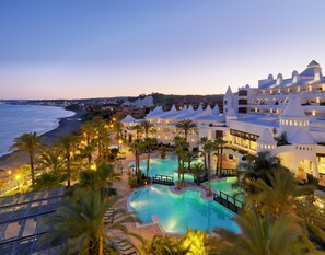 Un resort con piscina, palmeras y vista a la playa.