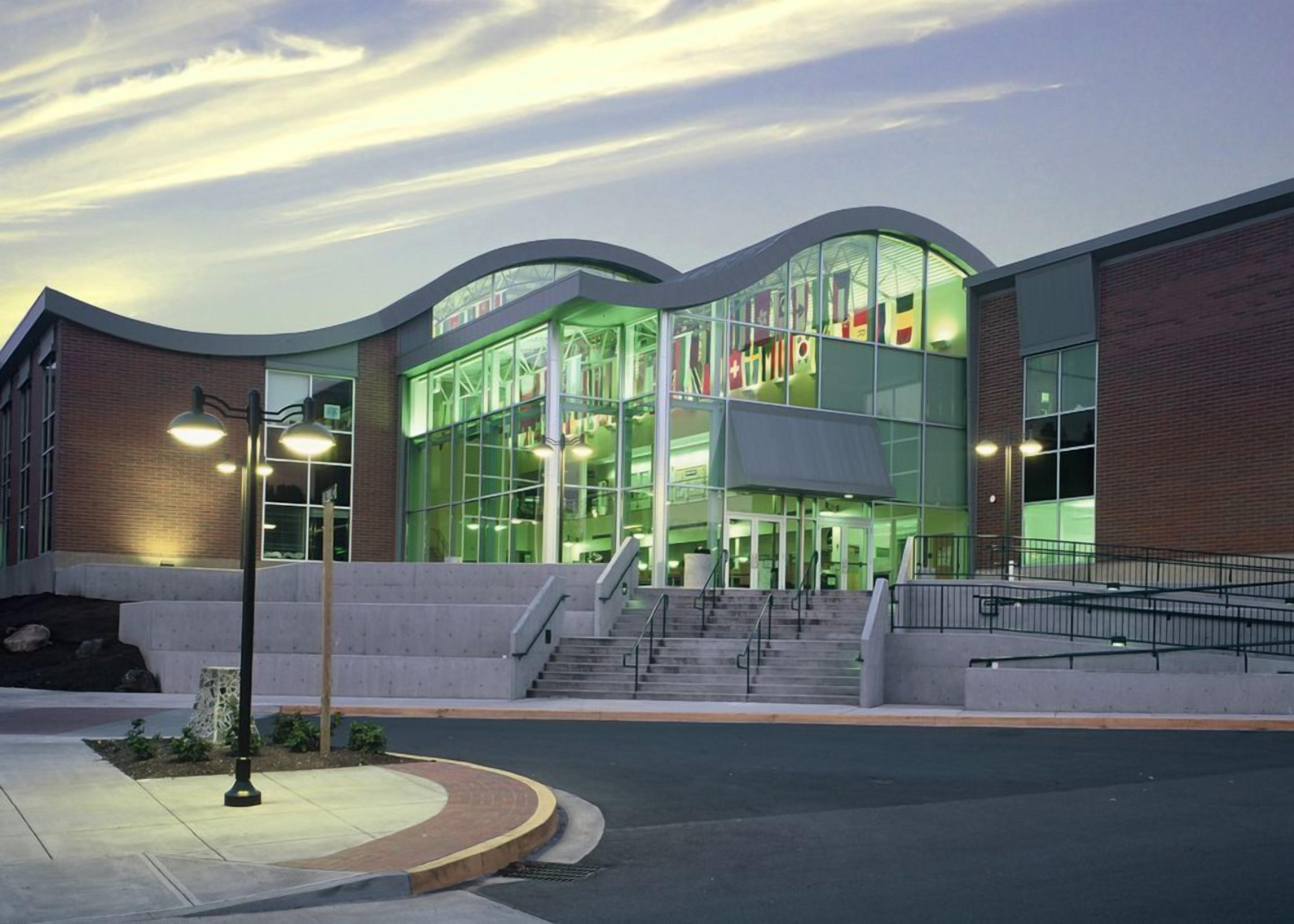 A modern building with large glass windows, a brick facade, and a set of stairs leading to the entrance.