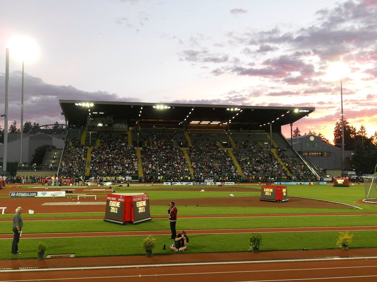 A stadium with tiered seating, a track, and a field.