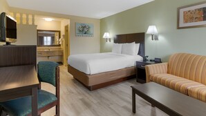 A hotel room with a bed, a desk, a chair, a sofa, and a TV.