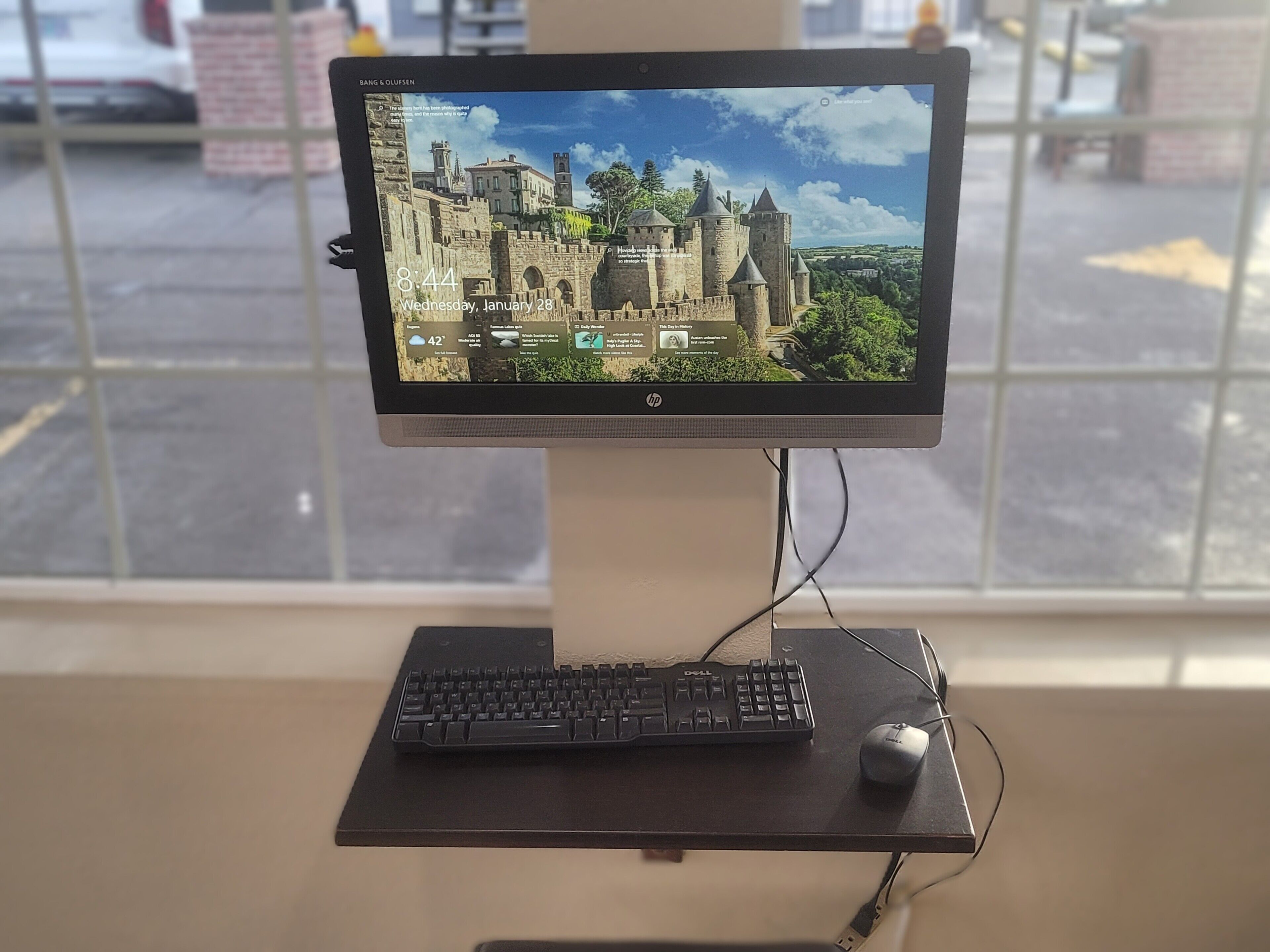 A desktop computer setup with a monitor displaying a castle image, a keyboard, and a mouse on a desk.