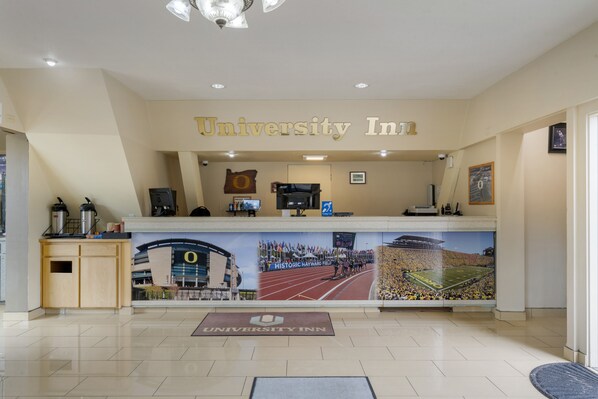 Um balcão de recepção com uma grande faixa exibindo um evento de atletismo, um espaço para café e uma placa com o dizer 'University Inn'.
