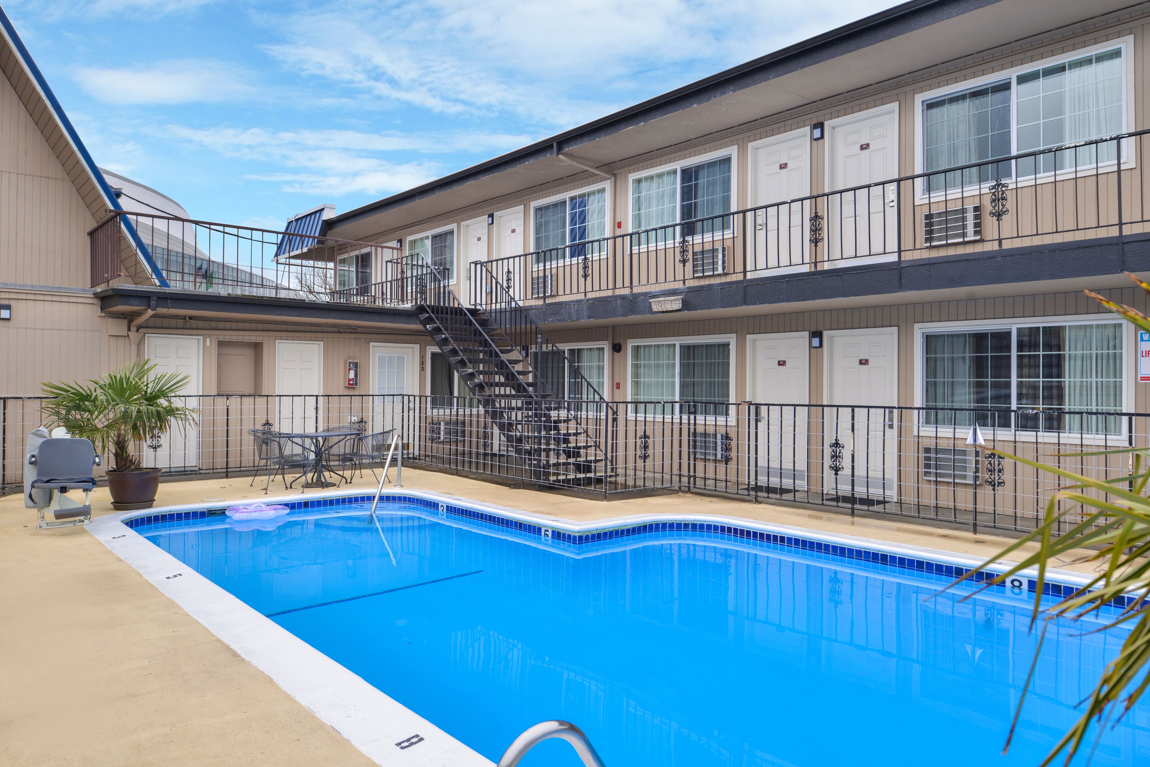 A two-story hotel with a swimming pool, outdoor seating, and a barbecue area.