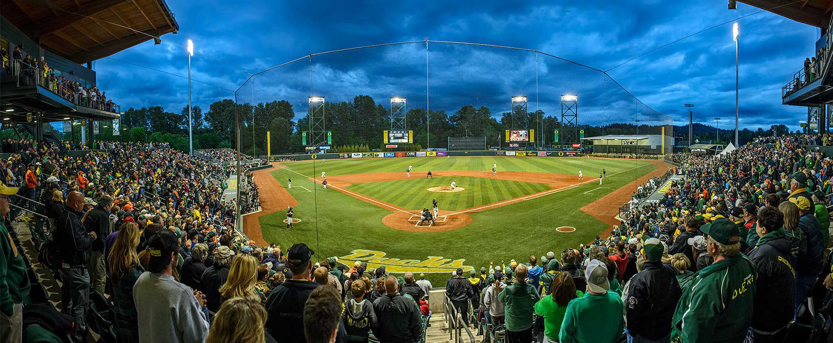 Un estadio de béisbol con una multitud numerosa, varios niveles de asientos y un campo bien iluminado.