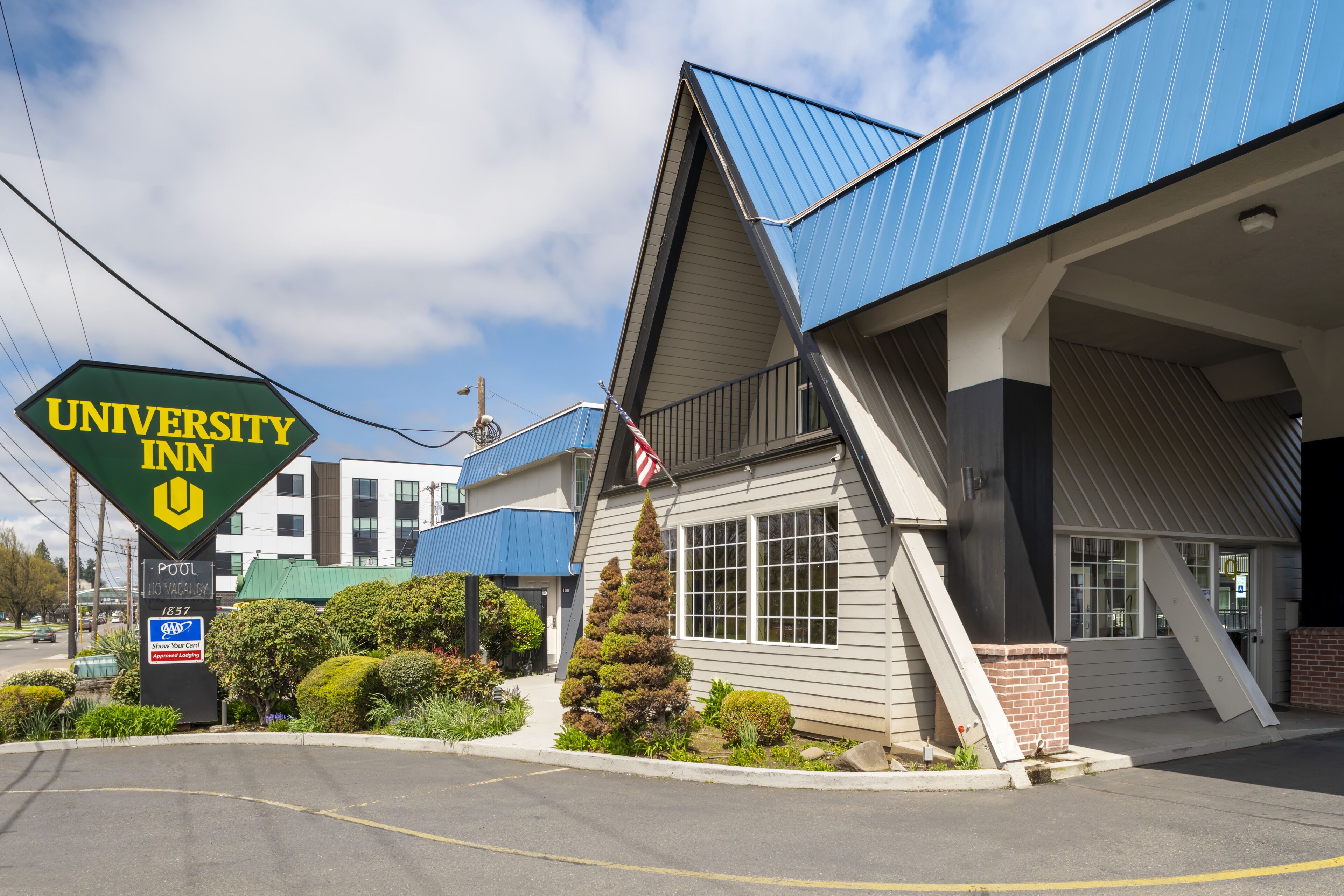 A University Inn building with a blue roof, a sign indicating a pool, and a parking lot.