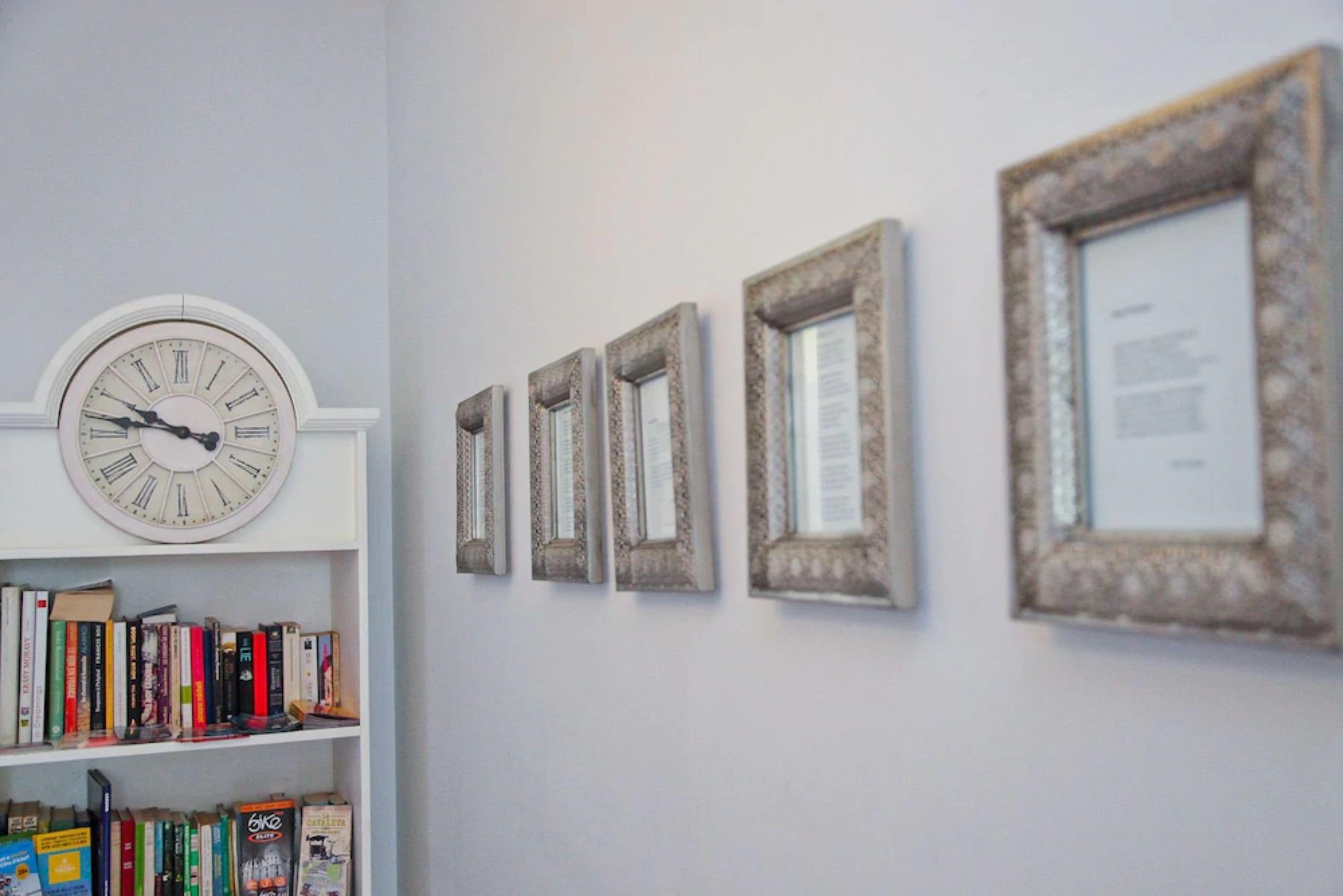 A wall with a clock and framed pictures.