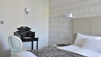 Ein Hotelzimmer mit Bett, Schreibtisch, Stuhl und Wandlampe.