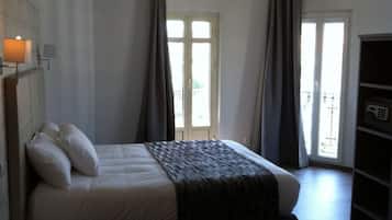 Un dormitorio con cama, mesita de noche, armario y ventana con cortinas.