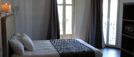 Une chambre à coucher comprenant un lit, une table de chevet, une armoire et une fenêtre avec des rideaux.