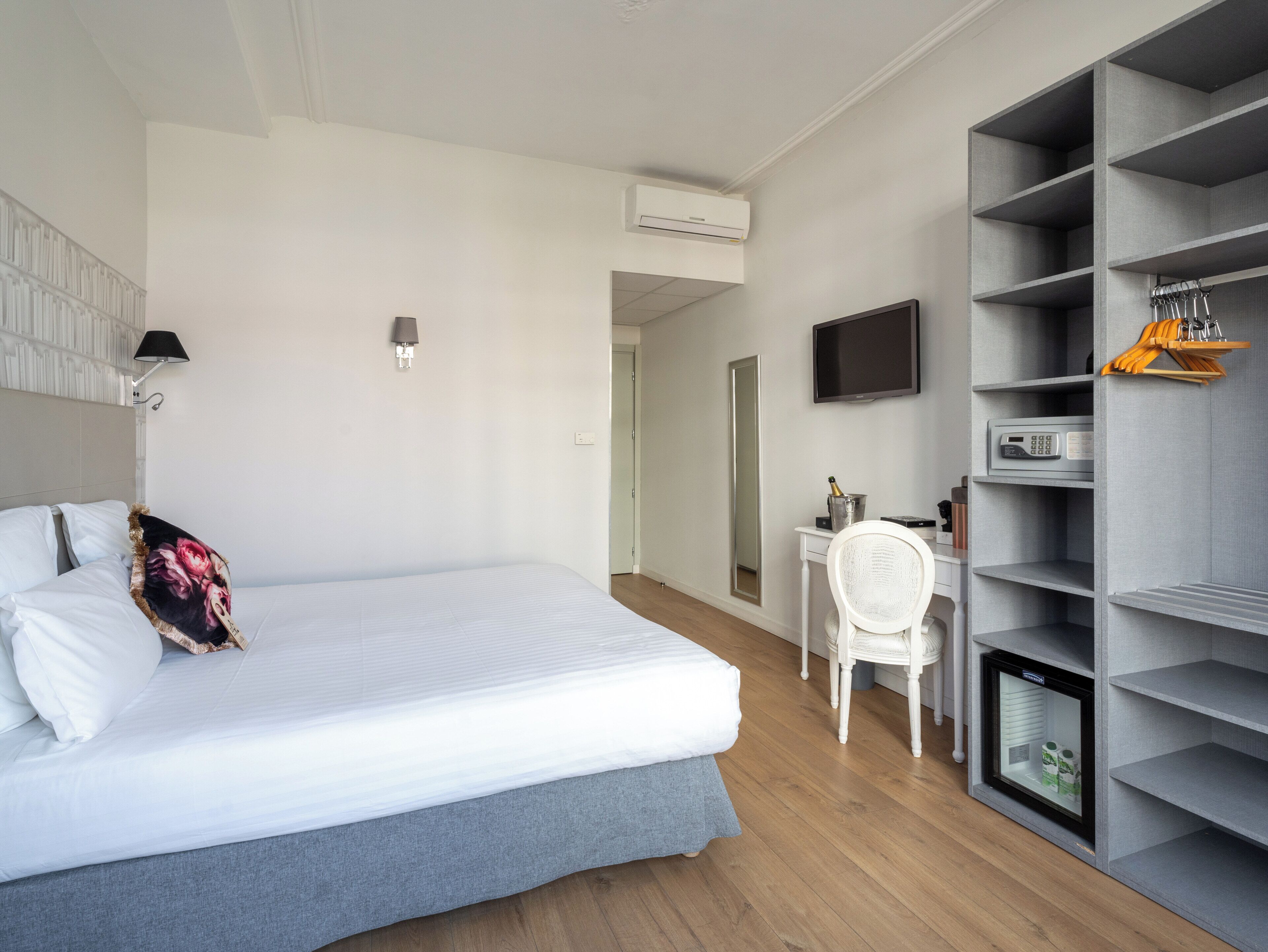 A bedroom with a bed, a desk, a chair, a TV, and a built-in wardrobe.