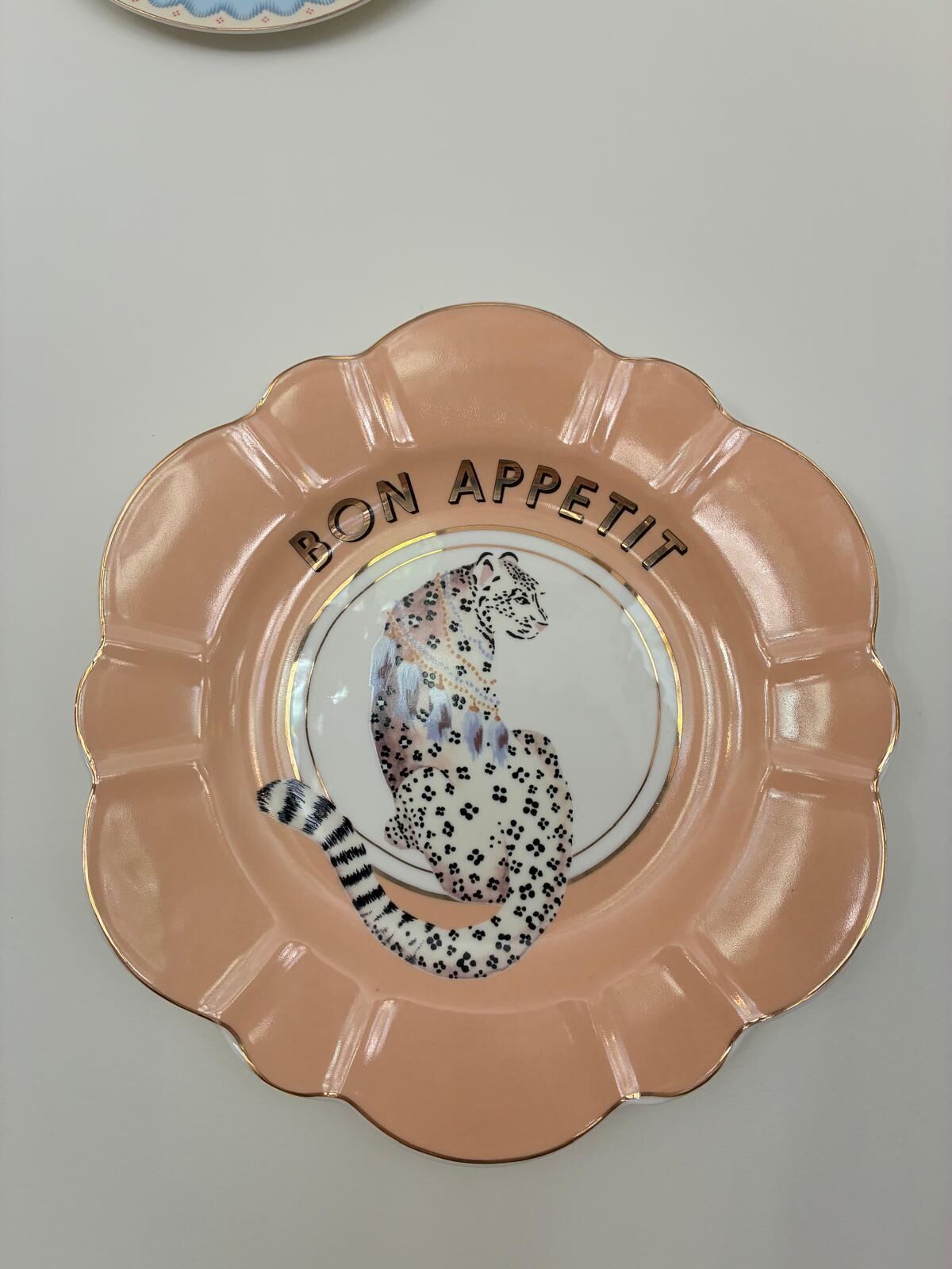 En dekorativ tallerken med et leopardmønster og teksten 'BON APPETIT' langs kanten.