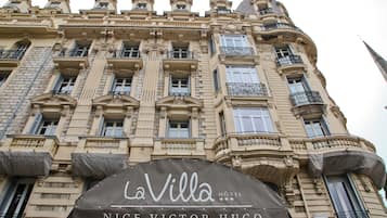 Fachada de hotel con detalles arquitectónicos ornamentales, un letrero que dice "LaVilla HOTEL NICE VICTOR HUGO" y una aguja destacada.