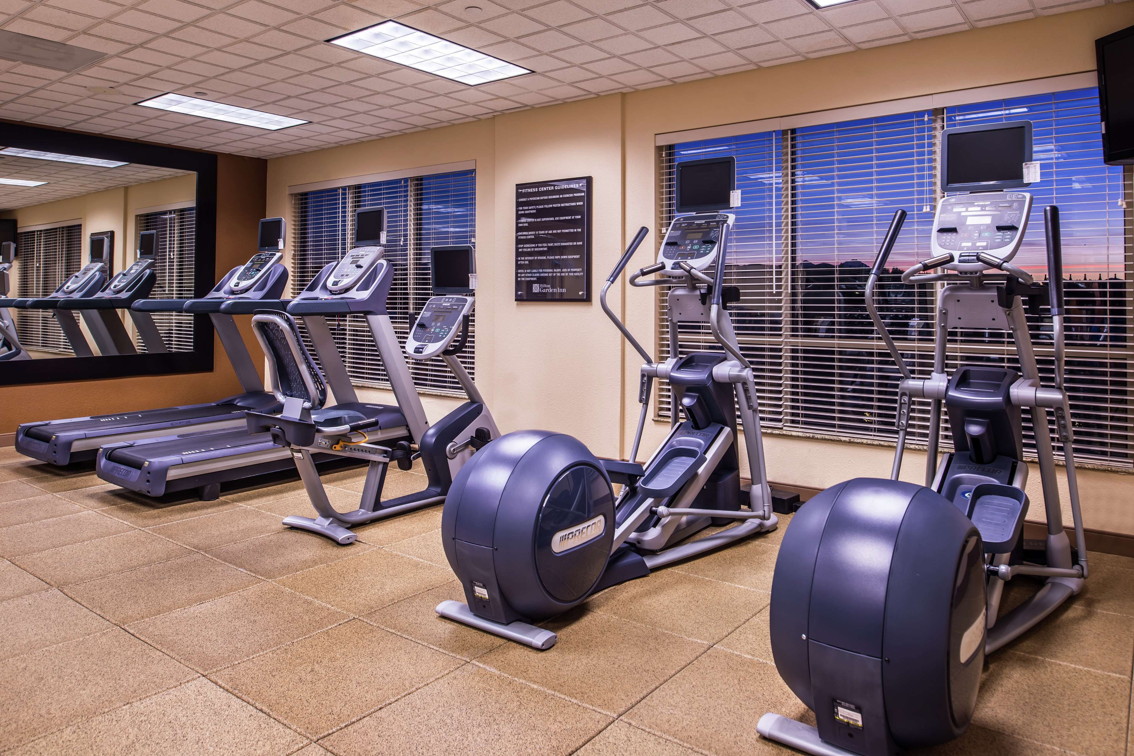 Un gimnasio con cintas de correr, elípticas y bicicletas estáticas.