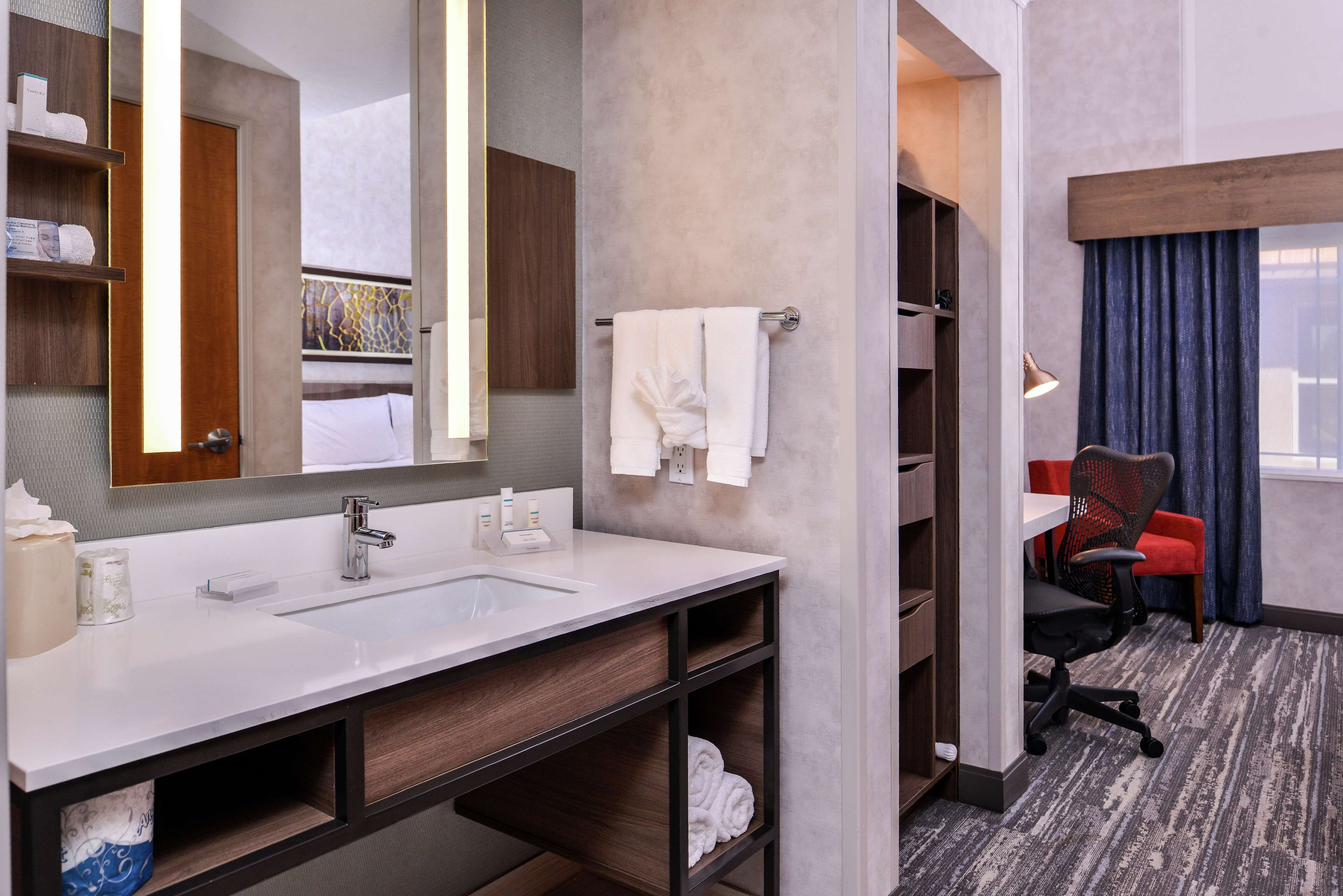 A modern bathroom with a large sink, mirror, and towel rack.