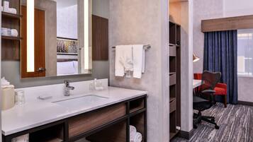 A modern bathroom with a large sink, mirror, and towel rack.