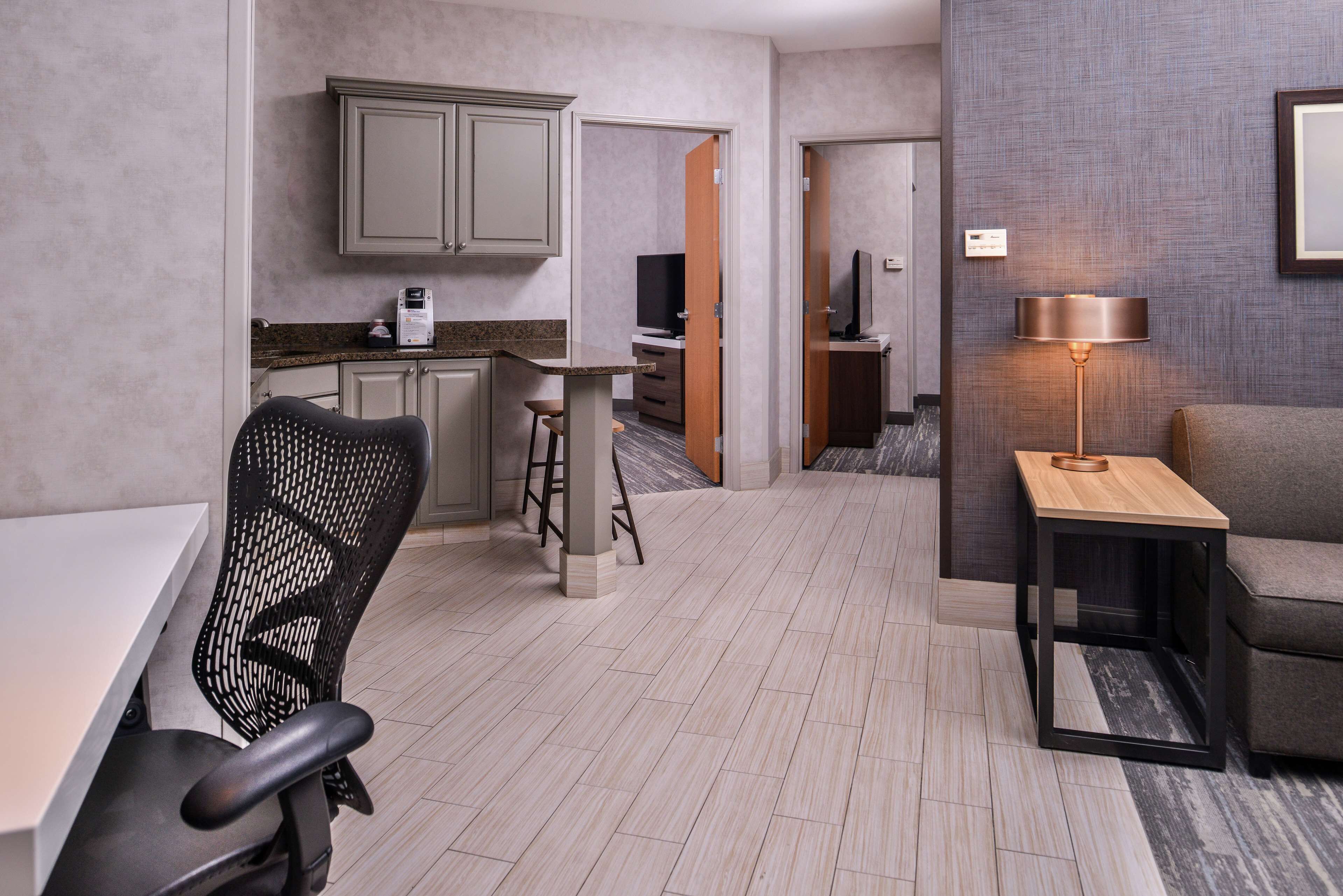 A modern hotel room with a dining area, a kitchen, and a living area.