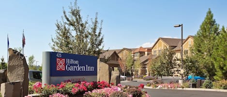 A Hilton Garden Inn sign with a flower garden in front.