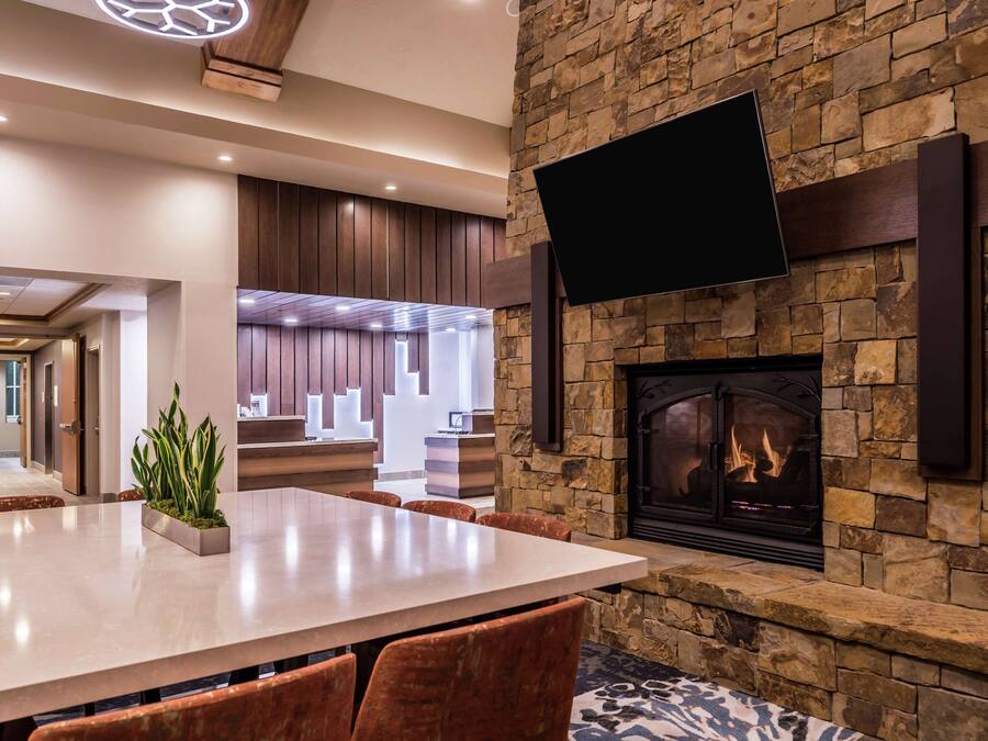 Un interior moderno con chimenea de piedra, un televisor de pantalla plana montado encima y un área de comedor con una mesa y sillas de mármol.