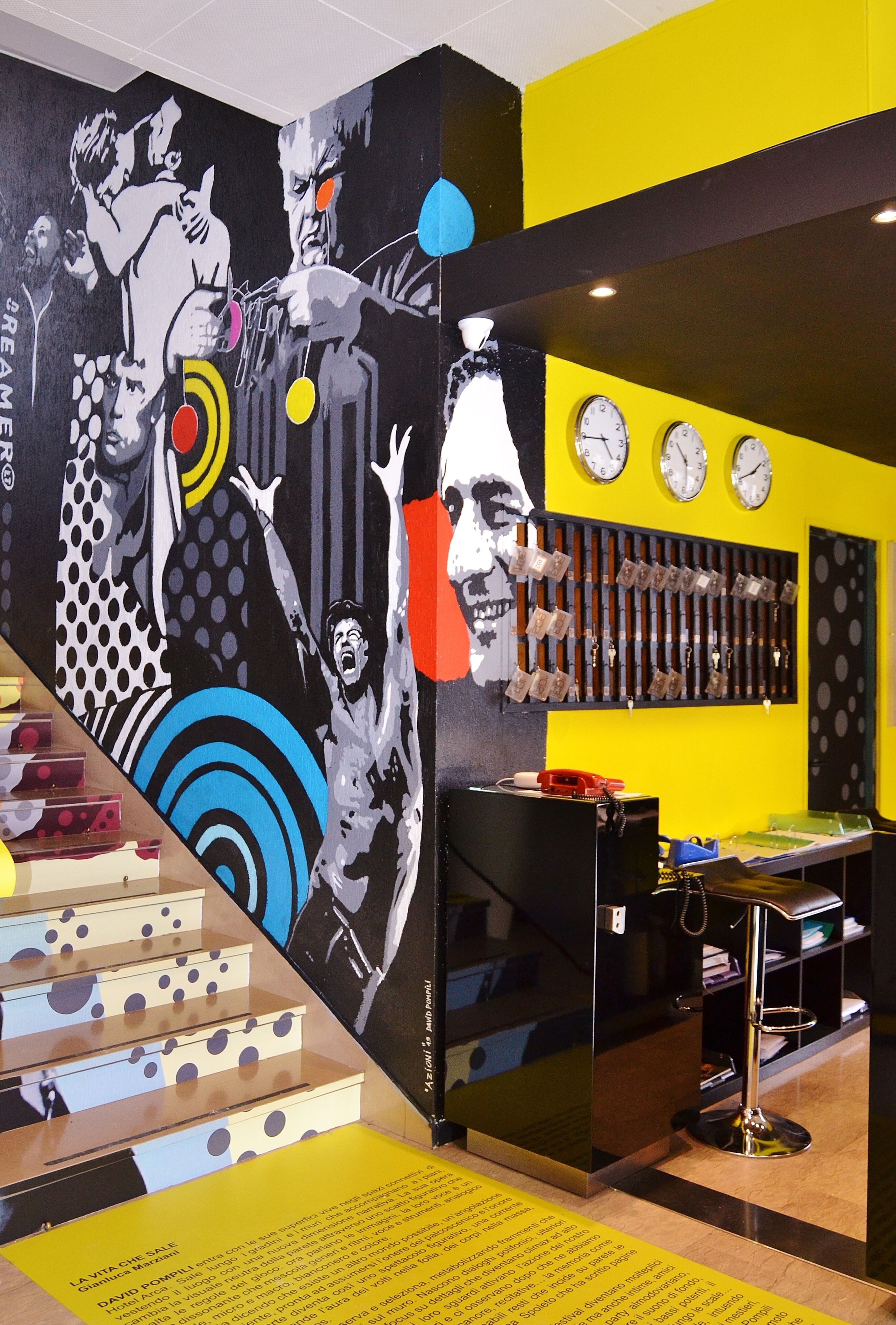 A vibrant room with a large abstract mural, a clock, and a telephone on a desk.