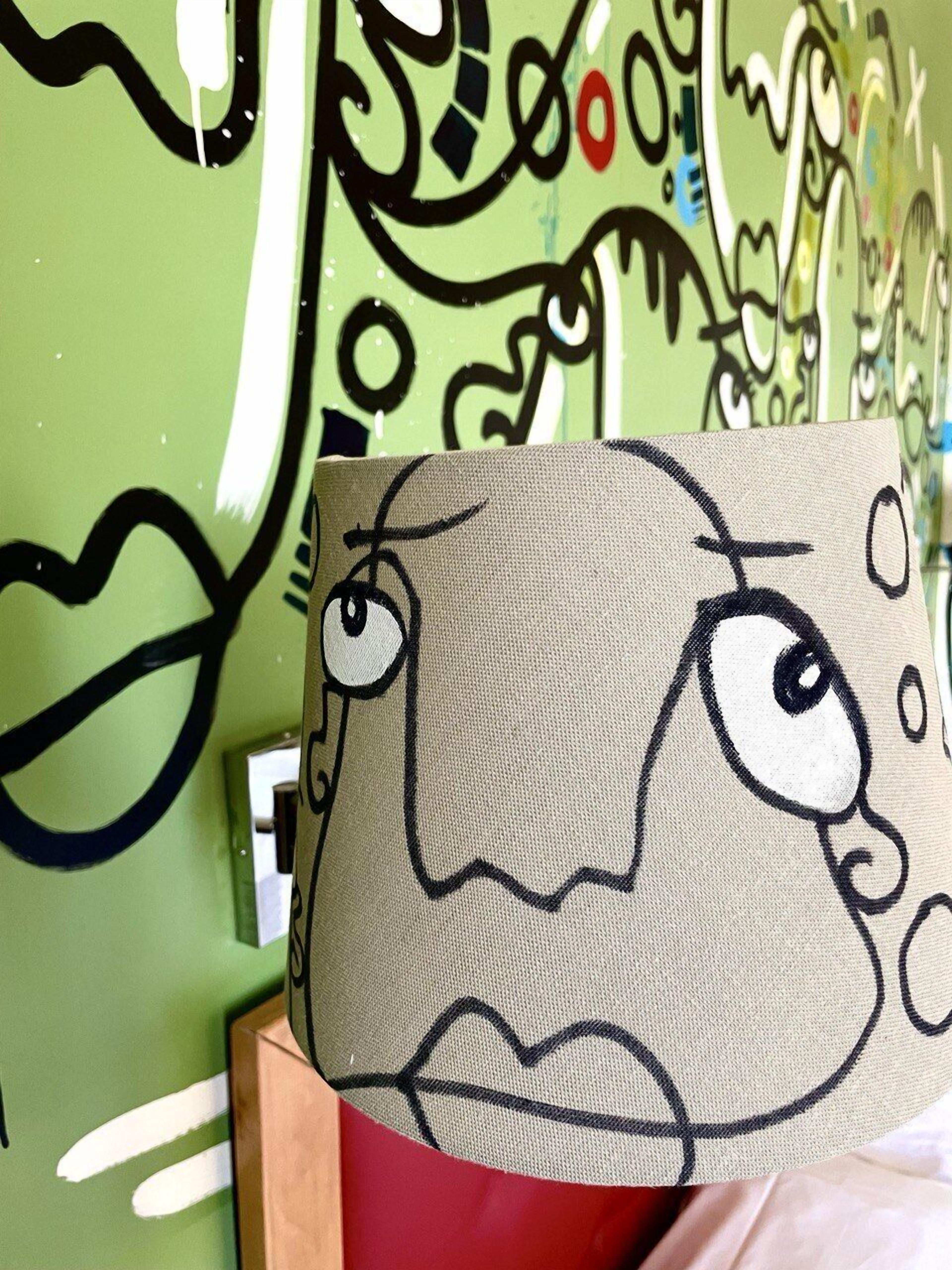 A painting of a face with large eyes and a nose, placed on a table with a green wall in the background.