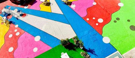 A colorful outdoor area with a large blue and white mural, seating areas, and small plants.