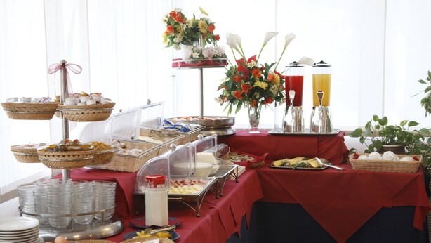 A buffet setup with various food items and a floral centerpiece. - Hotel Bamby (Rimini)