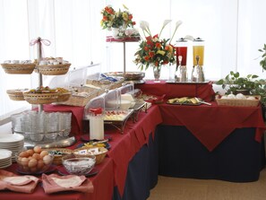 Un buffet proposant une variété de plats et agrémenté d’un arrangement floral en guise de décoration centrale.