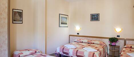 A hotel room with two beds, a headboard, wall-mounted lights, and framed artwork.