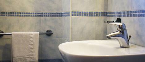 A bathroom with a sink, faucet, and towel rack.