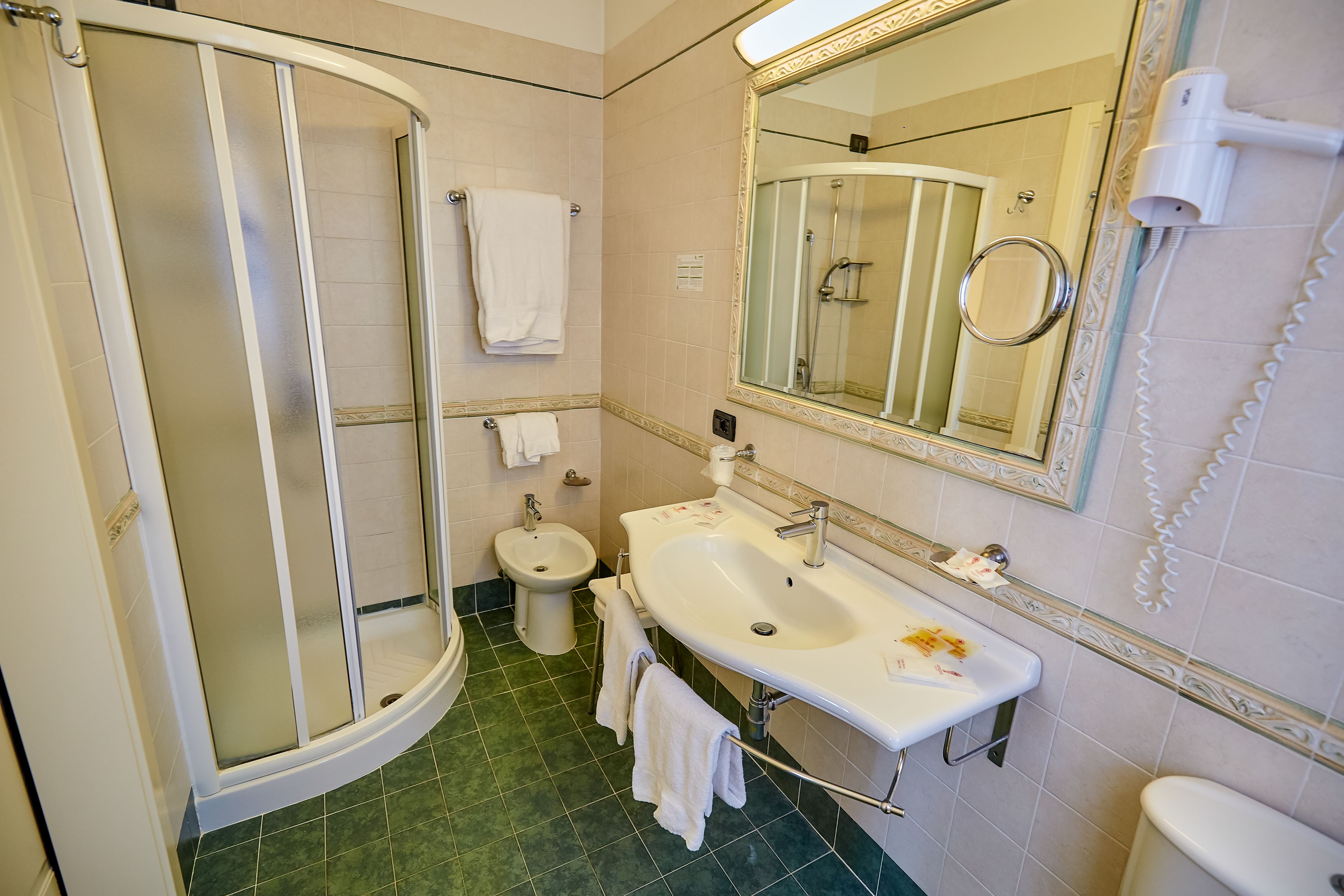 A bathroom with a glass-enclosed shower, a sink with a mirror, and a toilet.