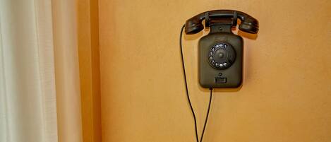 A rotary dial telephone mounted on a wall.