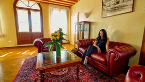 Un salon avec un canapé en cuir rouge, une table basse en verre agrémentée d’un arrangement floral et un tapis à motifs.