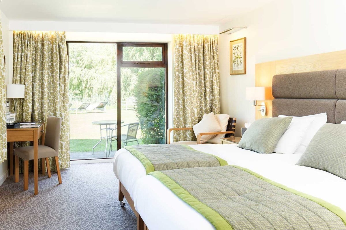A hotel room with two beds, a desk, and a chair.