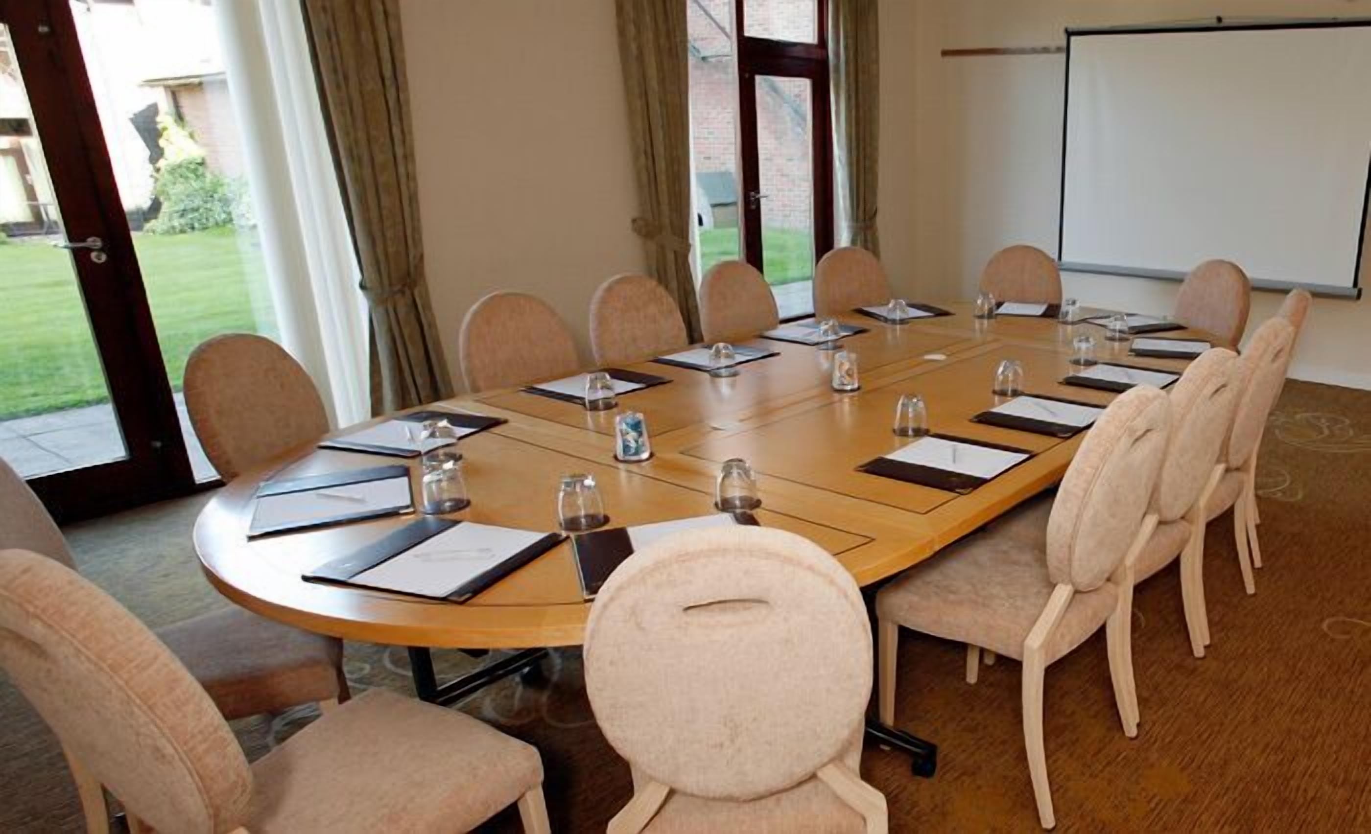 A conference room with a long table, chairs, and a whiteboard.