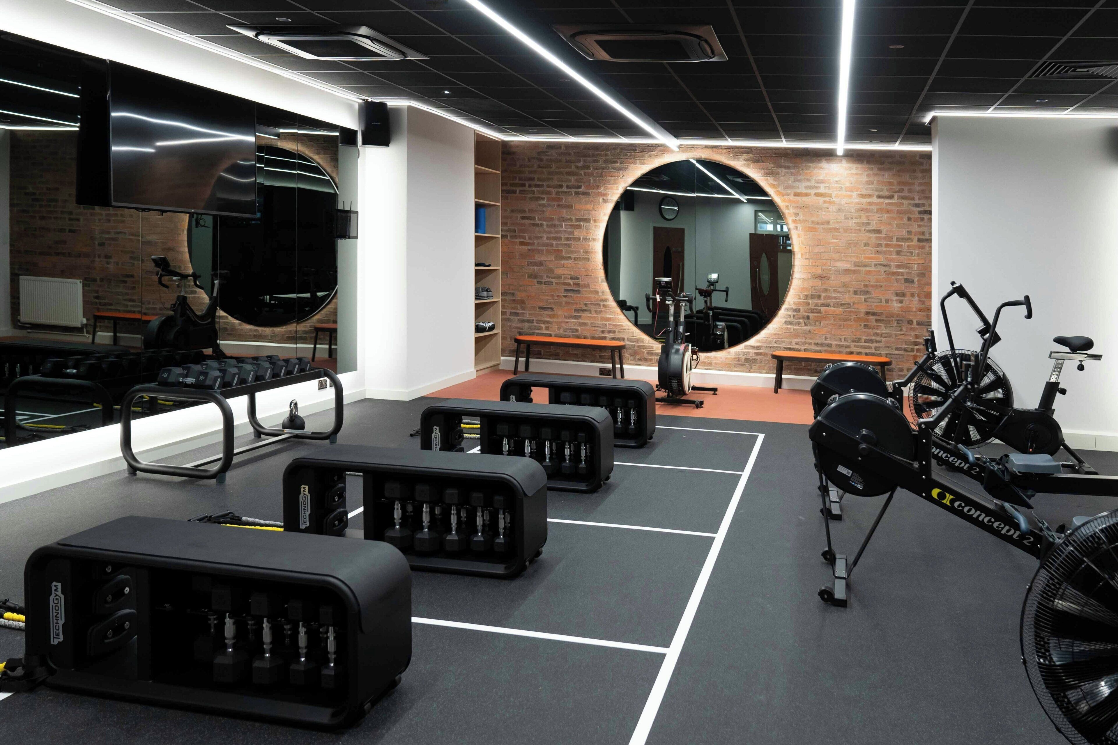 A gym with exercise equipment, a mirror, and a brick wall.