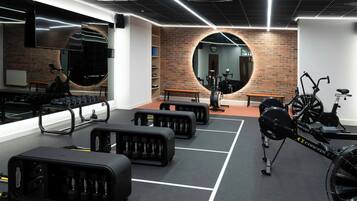 A gym with exercise equipment, a mirror, and a brick wall.